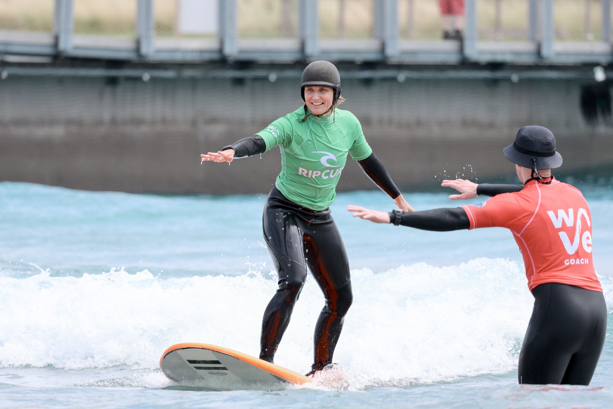 Woman learning to surf in an adult beginner lesson at The Wave Bristol.