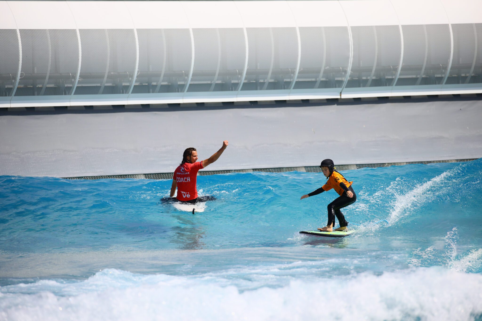 A child surfs with a coach in a Little Improvers Surf Lesson at The Wave Bristol