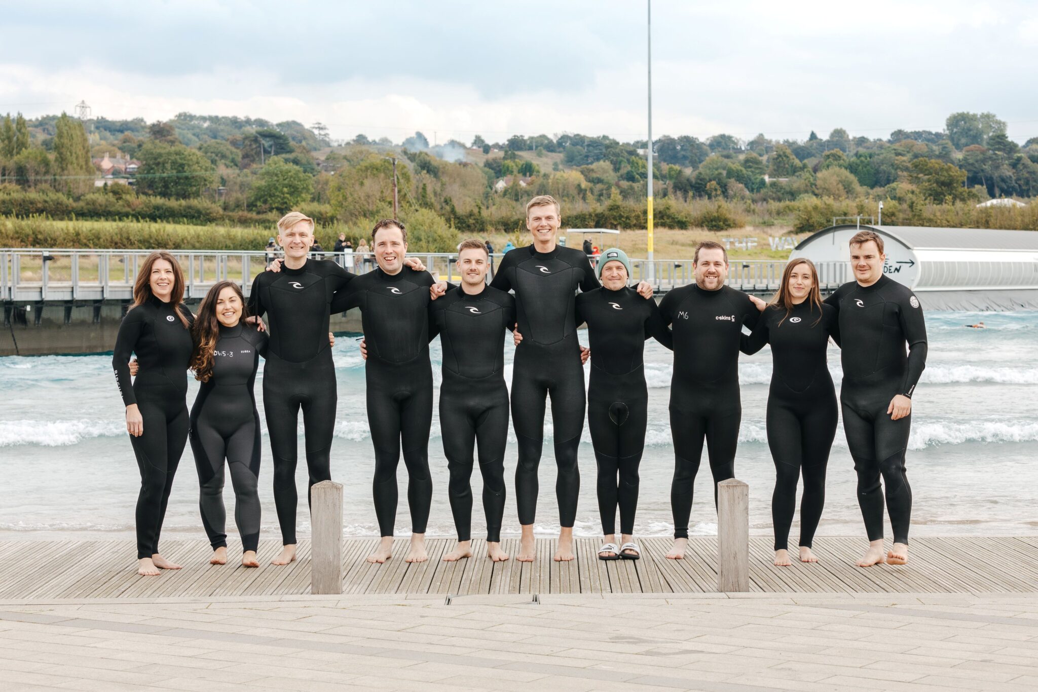 A group of colleagues pose for a photo in front of the lake at The Wave Bristol.