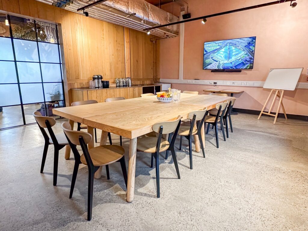 The Hideaway meeting room with a long table, chairs and screen at The Wave Bristol.